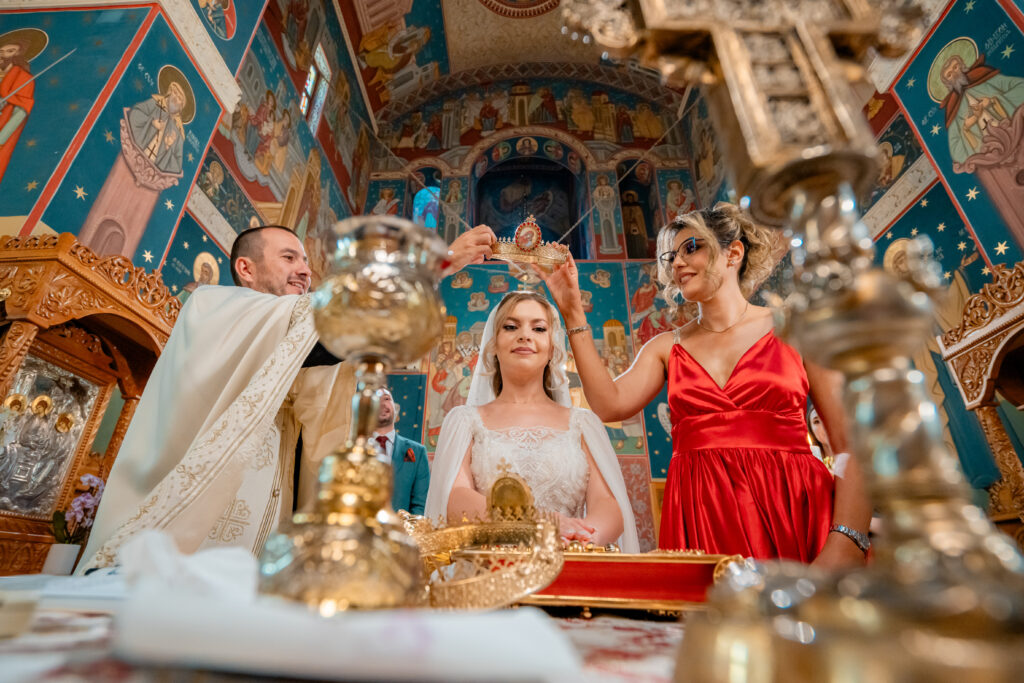 Momentul punerii cununiilor în cadrul ceremoniei religioase de nuntă, surprins în biserică