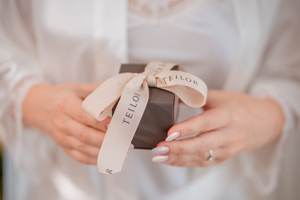 Detaliu din pregătirea miresei, cu o cutie de bijuterii legată cu panglică, surprinsă într-un cadru luminos