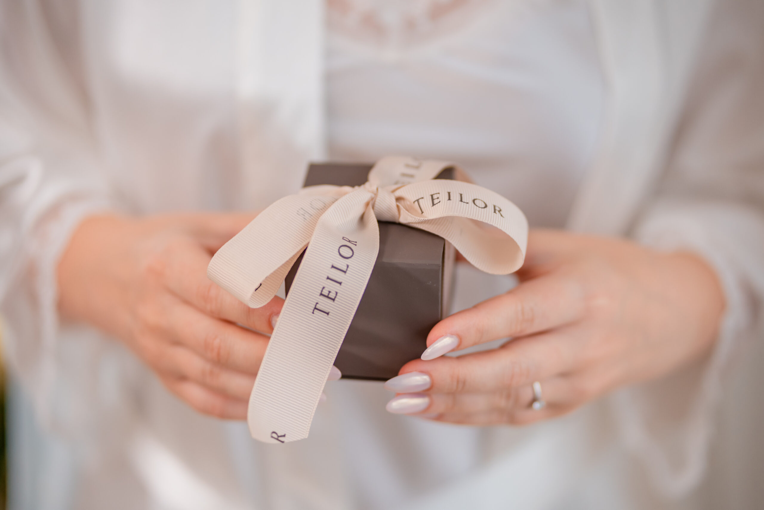 Detaliu din pregătirea miresei, cu o cutie de bijuterii legată cu panglică, surprinsă într-un cadru luminos