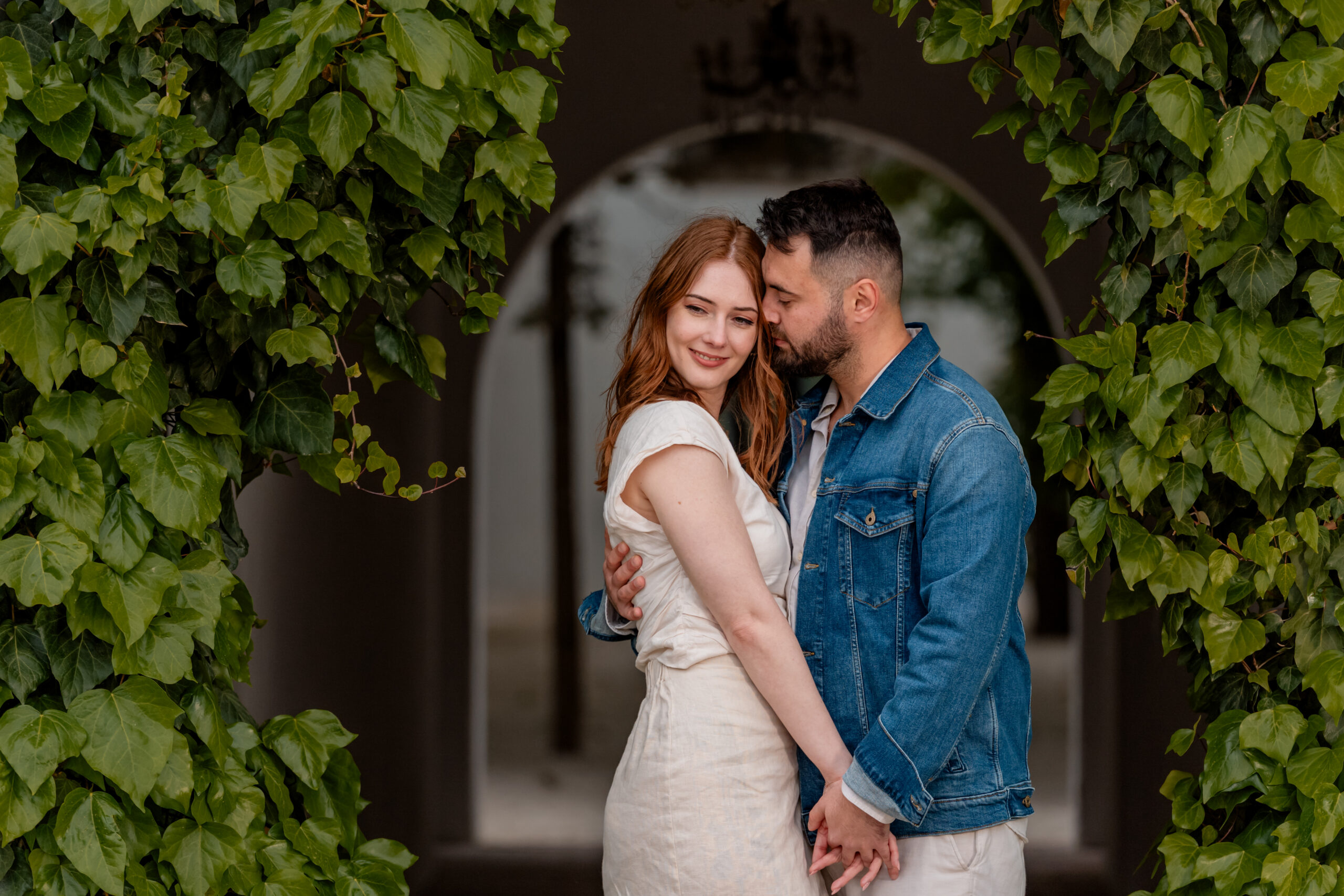 Cuplu într-o ședință foto pre-wedding, îmbrățișare într-un decor natural cu frunze verzi