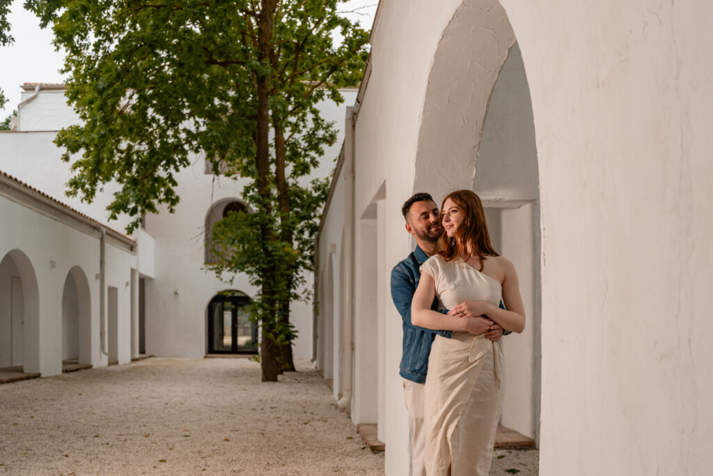 Cuplu într-o ședință foto pre-wedding, surprins într-un decor arhitectural elegant, cu arcade albe